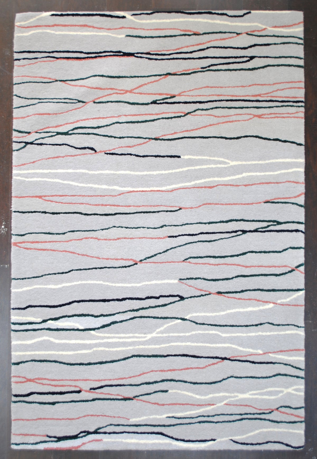 Chilika hand-tufted wool rug laid flat on a dark wooden floor, full overhead view