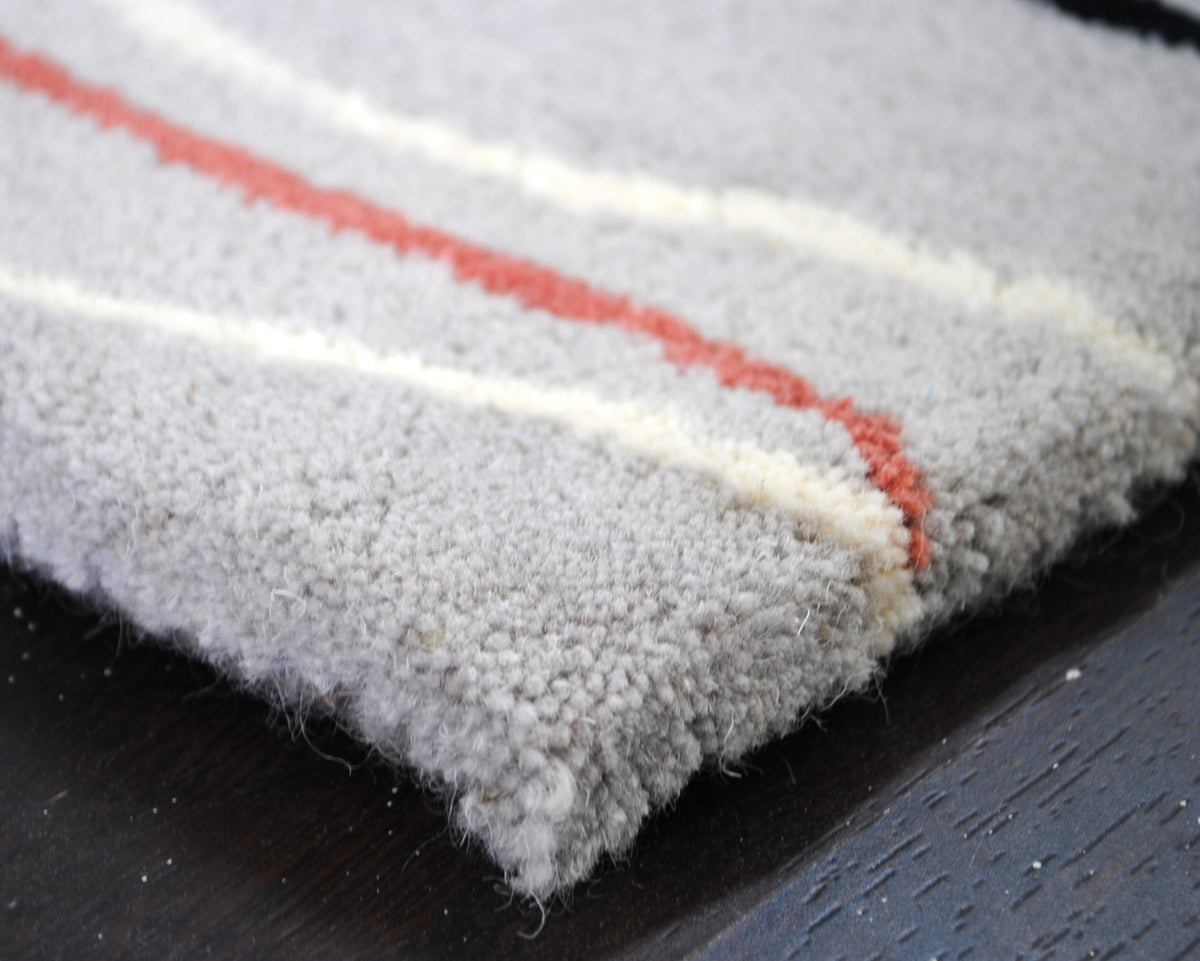 Close-up of the Chilika rug pile, a dusty rose and an ivory line tufted into the dove-grey wool