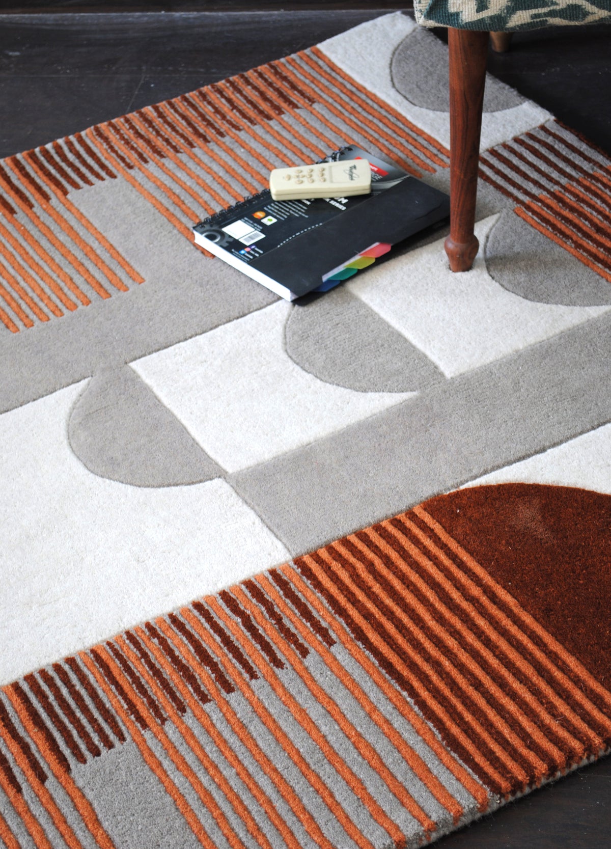 Ahmedabad terracotta and grey geometric rug viewed at an angle on a dark floor