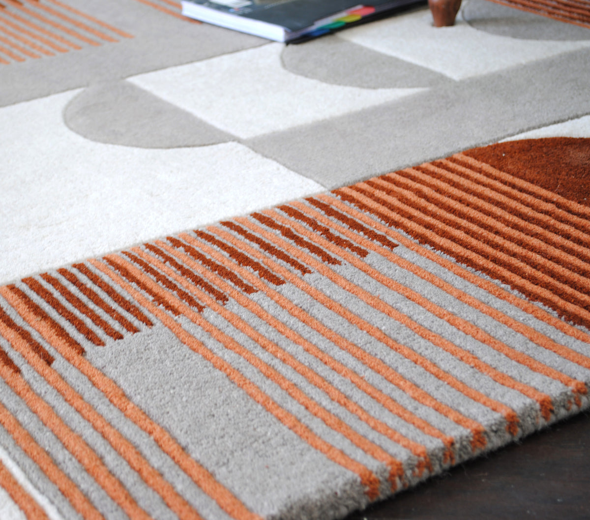 Low angle across the Ahmedabad rug showing rust and burnt orange stripes on grey beneath a rust arch