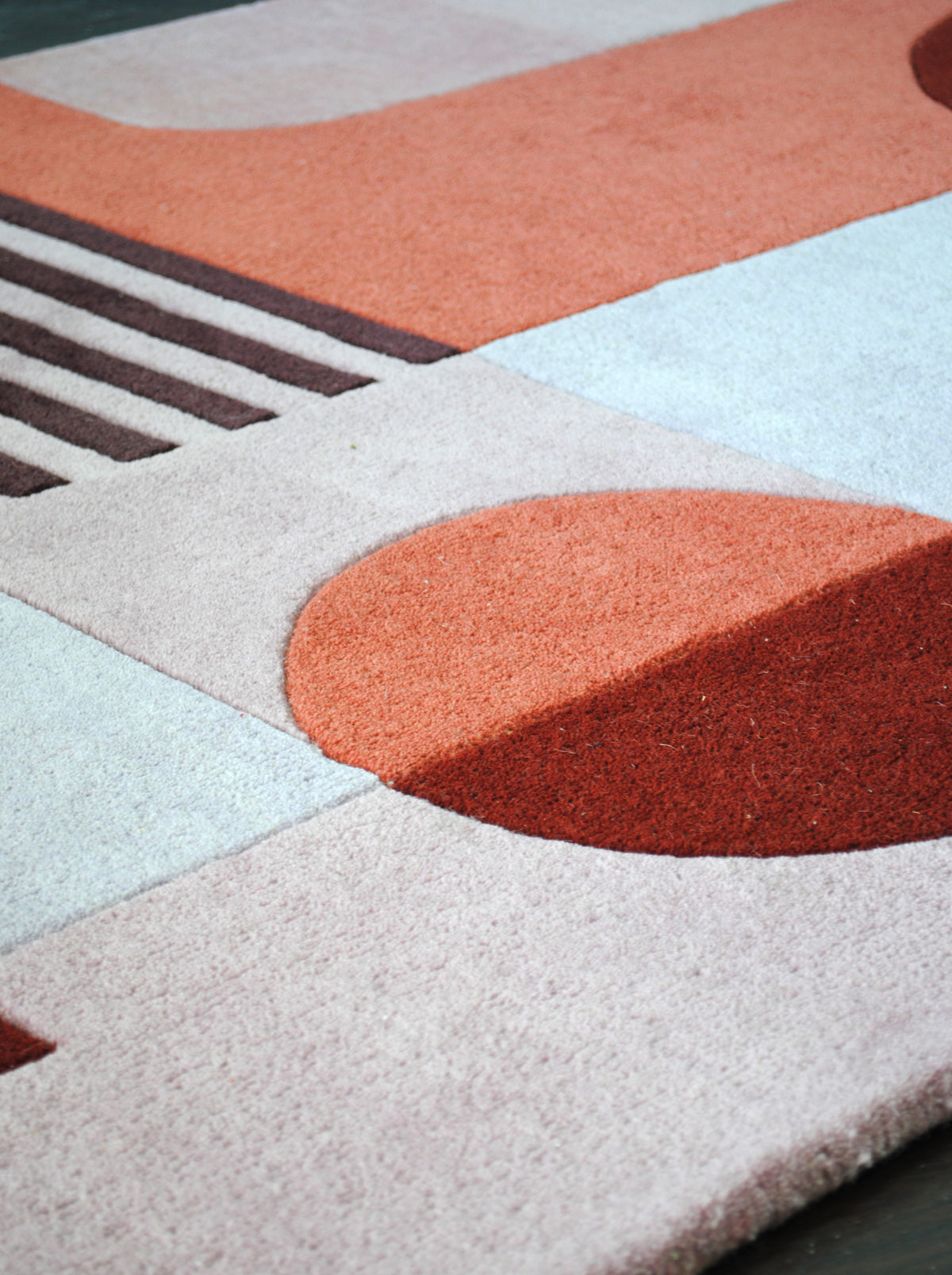 Plum pinstripes, a lilac grey block and a terracotta and rust disc on the Konark hand-tufted rug