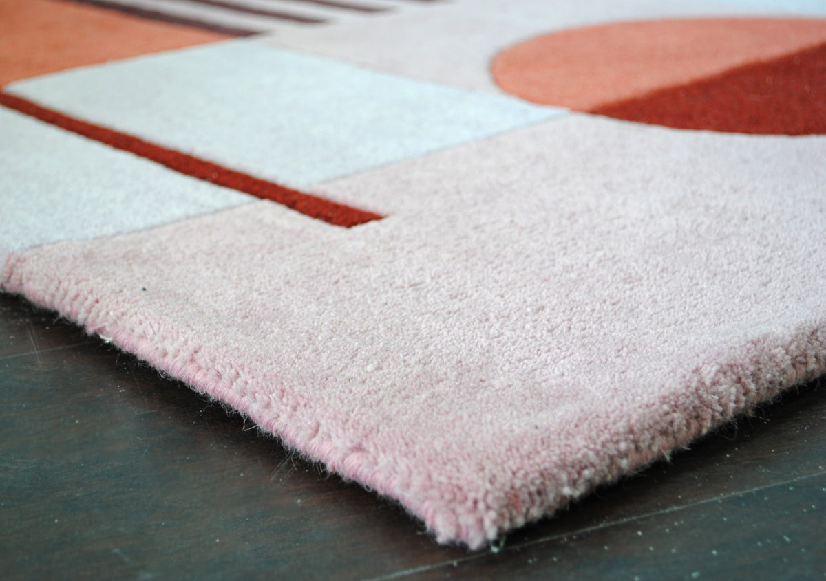 Edge of the Konark rug: dense sheared New Zealand wool pile in blush pink with a bound edge, no fringe