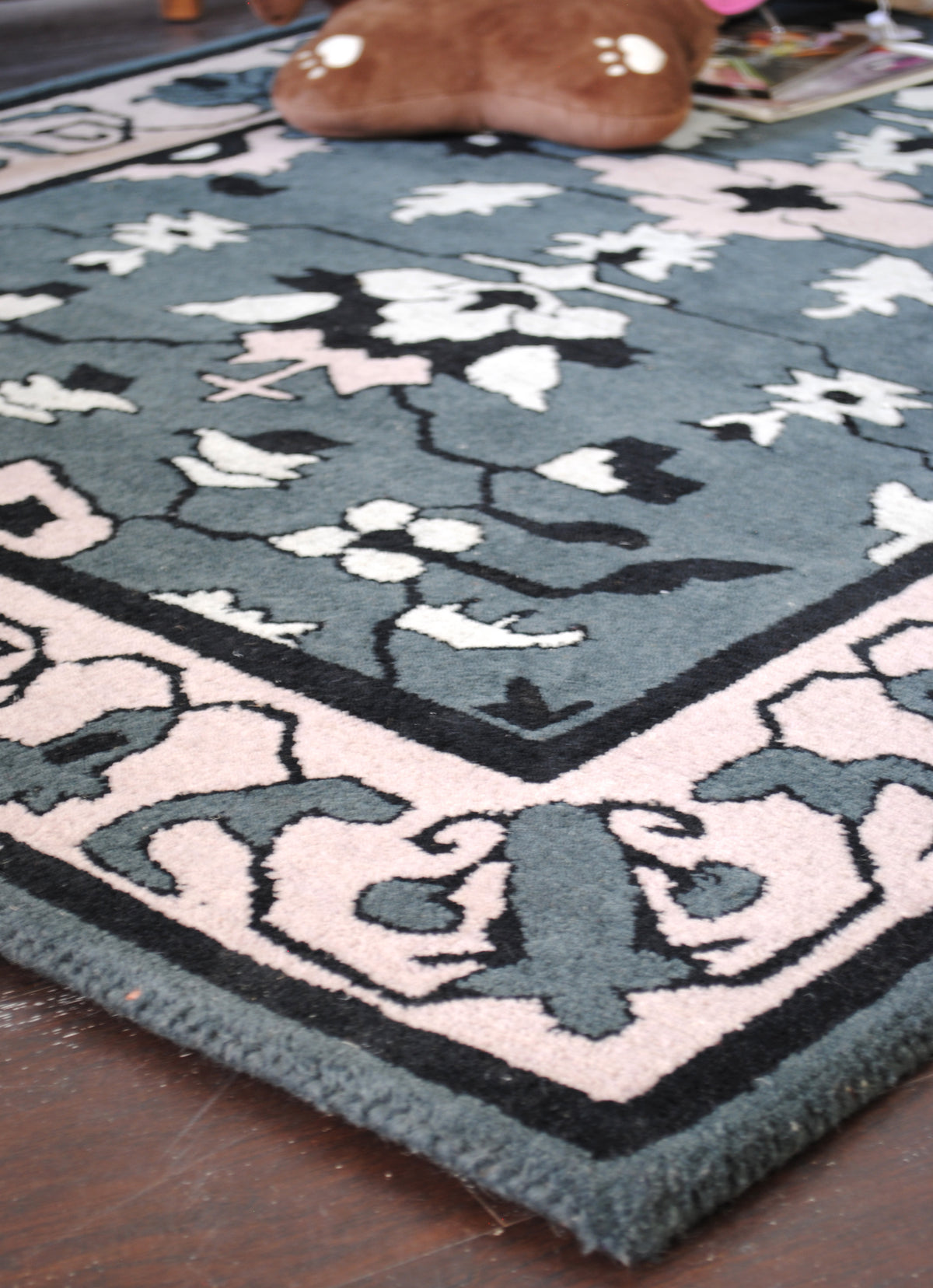 Corner of the Shimla hand-tufted rug: blush border, black guard lines and slate wool-bound edge, no fringe