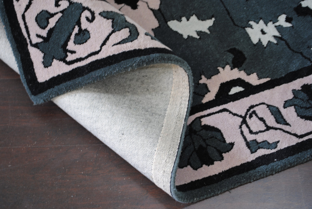 Folded corner of the Shimla rug showing the cotton canvas backing and slate wool-bound edge
