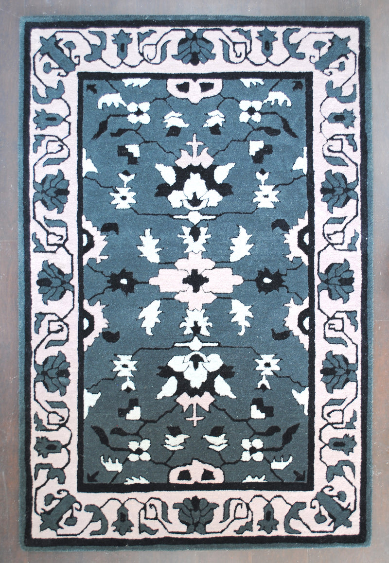 Shimla hand-tufted rug in 100% New Zealand wool, full overhead view: mirrored ivory and blush blossoms on a slate grey field with a wide blush scrolling-vine border, Art Avenue, 4×6 ft