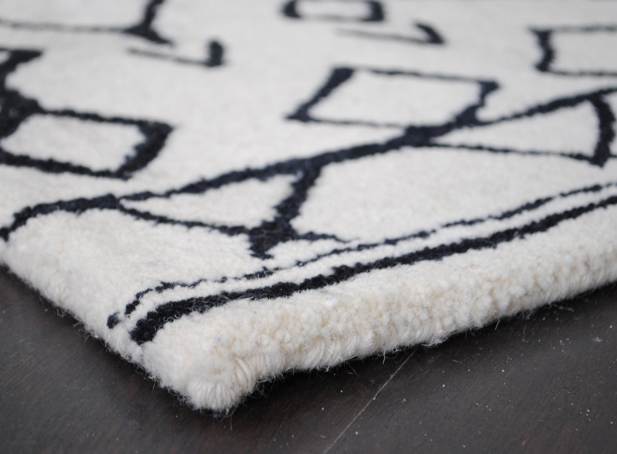 Ivory wool-bound edge of the Spiti Hand-Tufted Rug showing pile depth, no fringe — Art Avenue