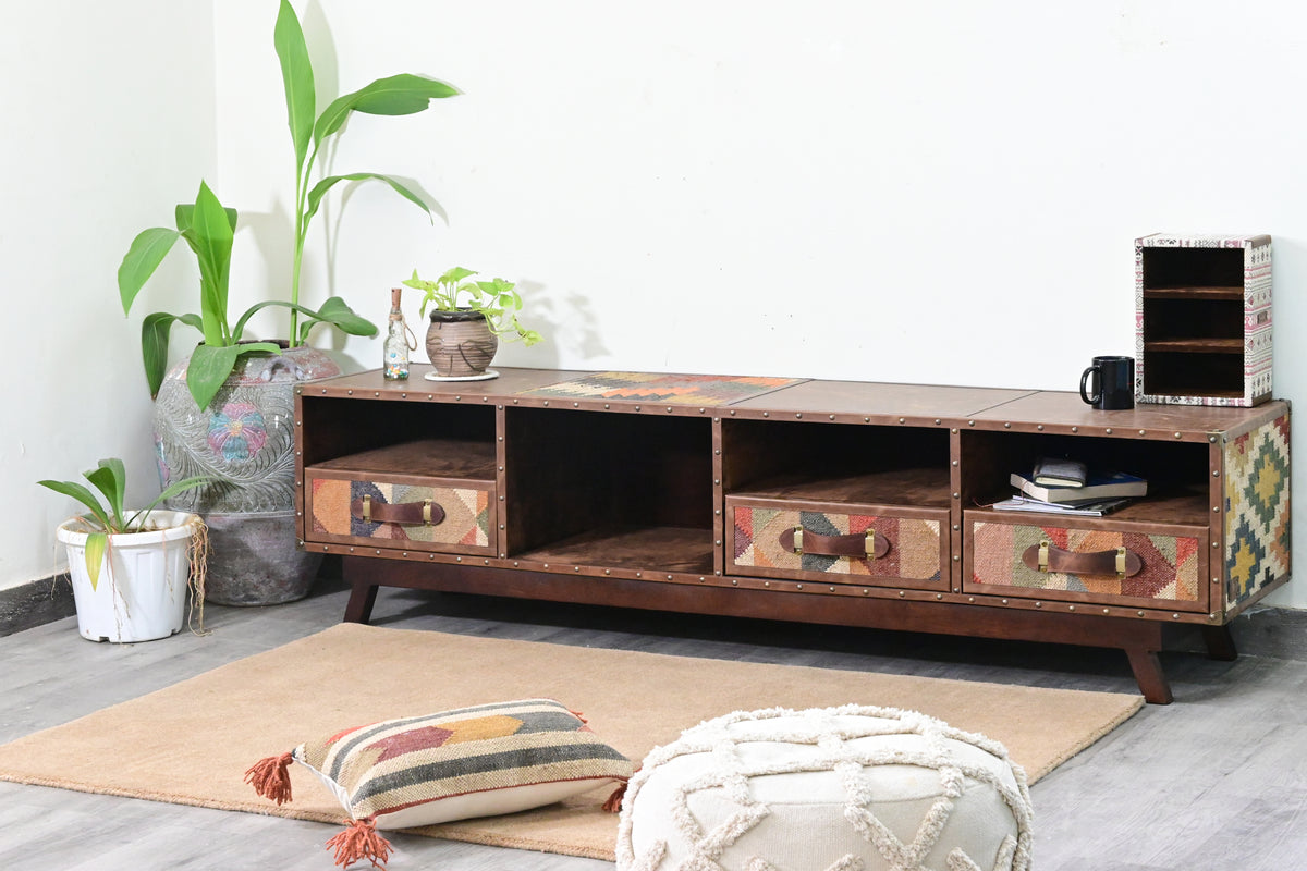 Ranakpur kilim and leather TV unit styled in a living room corner with plants, a kilim cushion and a tufted pouffe