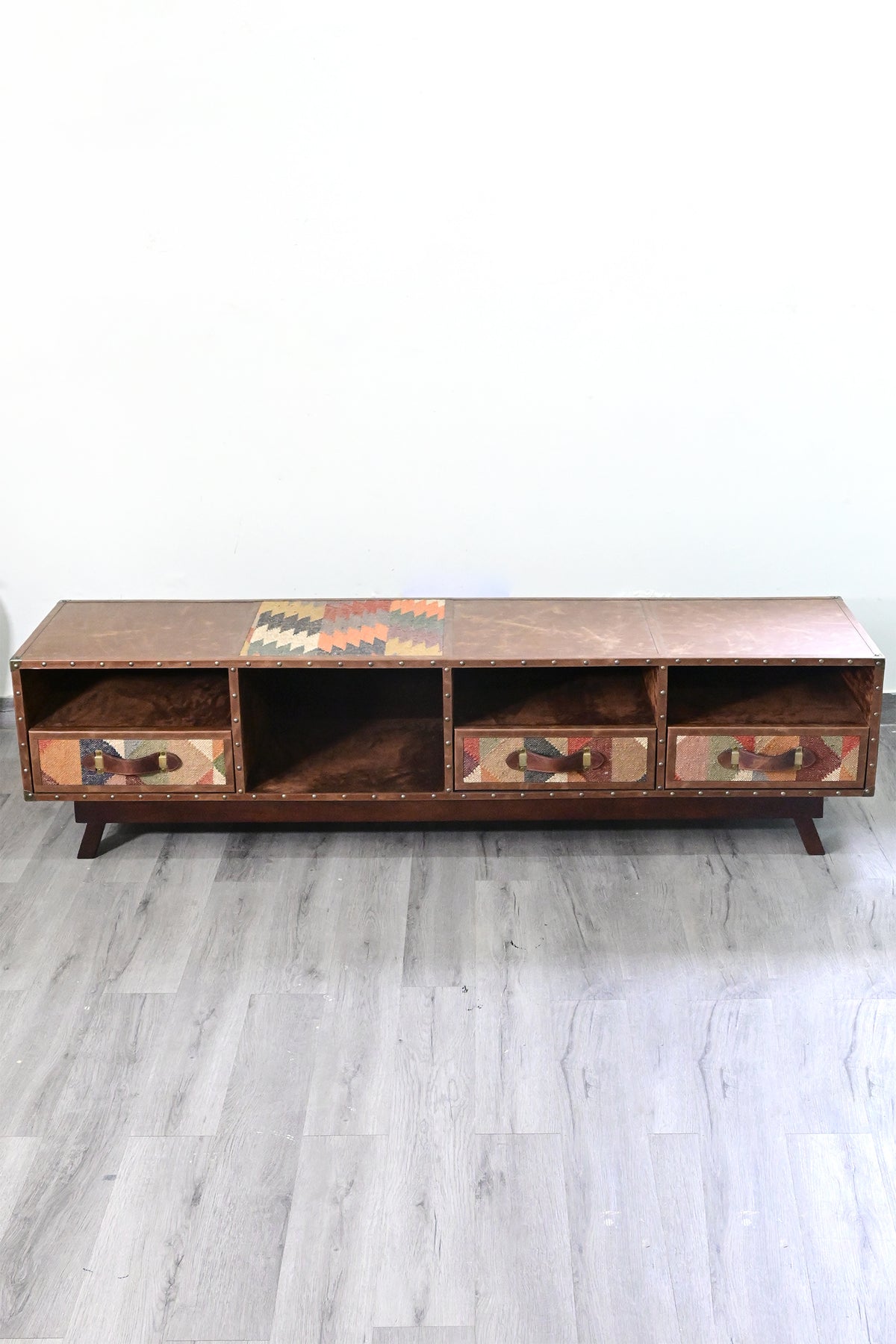 Elevated front view of the Ranakpur TV unit, leather top in four stitched panels with a vintage kilim inset