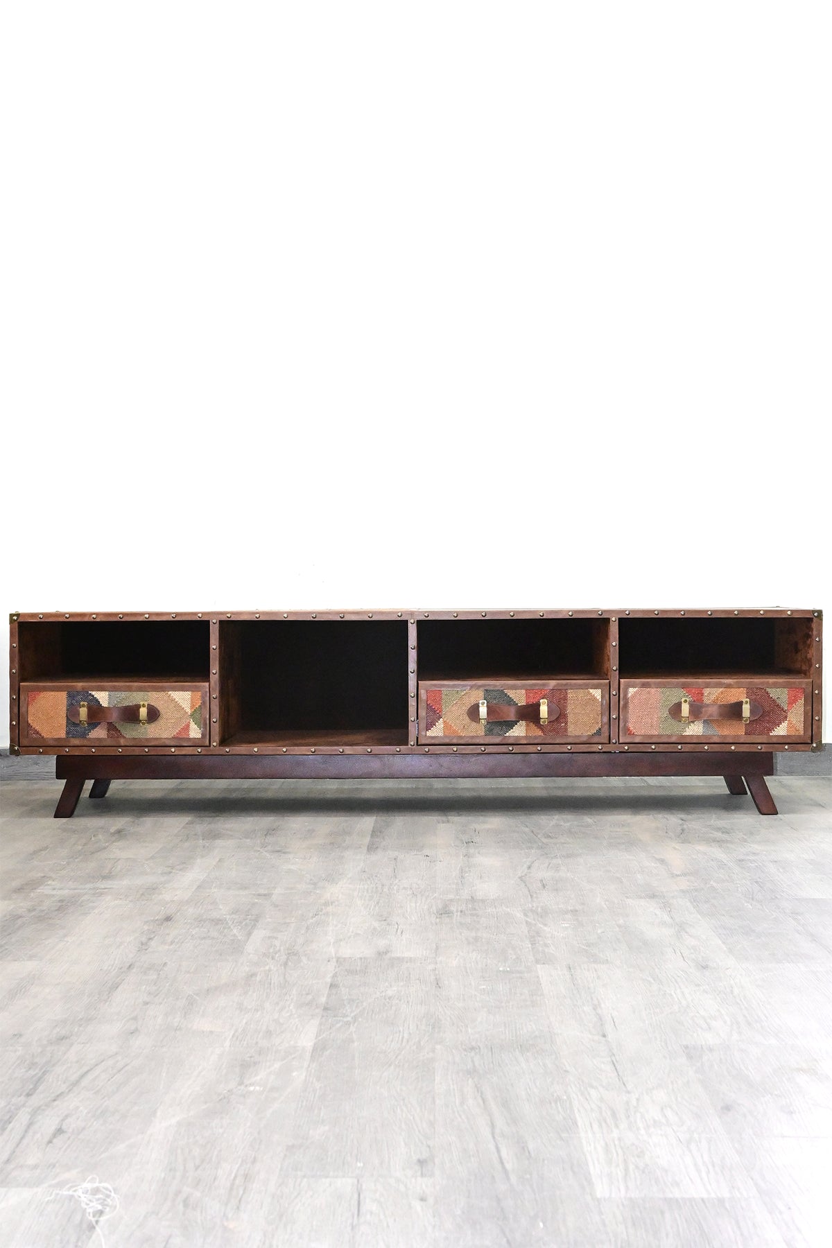Ranakpur kilim and leather TV unit seen straight on in the studio, four bays above a solid wood plinth with splayed legs