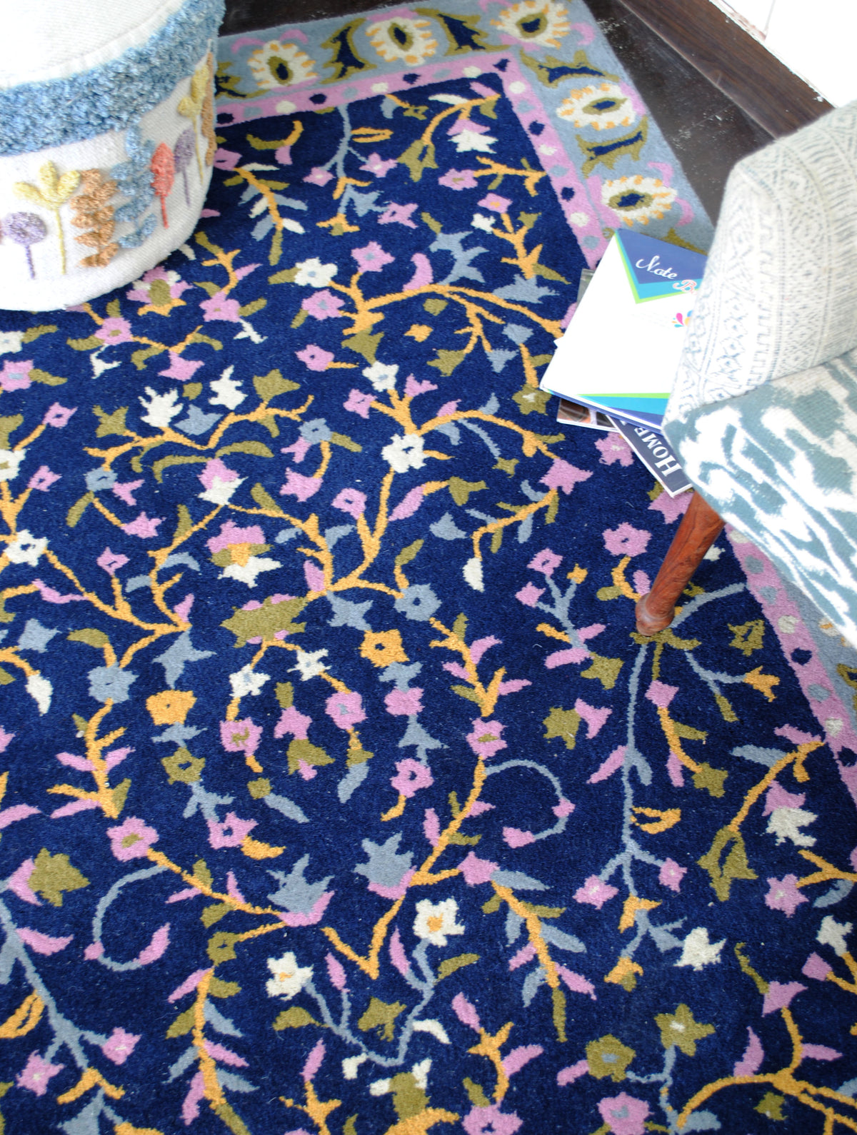 Top-down view of the Nishat rug's navy field with branching saffron vines and lilac, pink and ivory flowers
