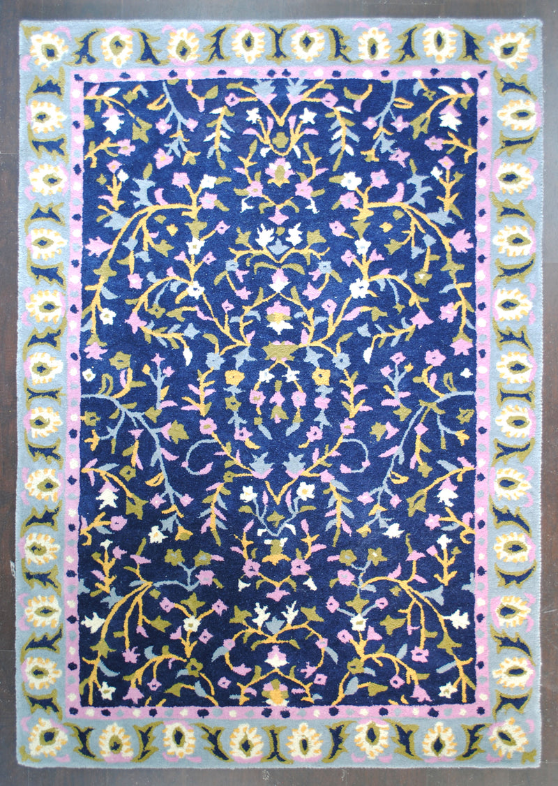 Nishat hand-tufted wool rug, full view: saffron vines, lilac and ivory blossoms on a navy field with a powder-blue floral border