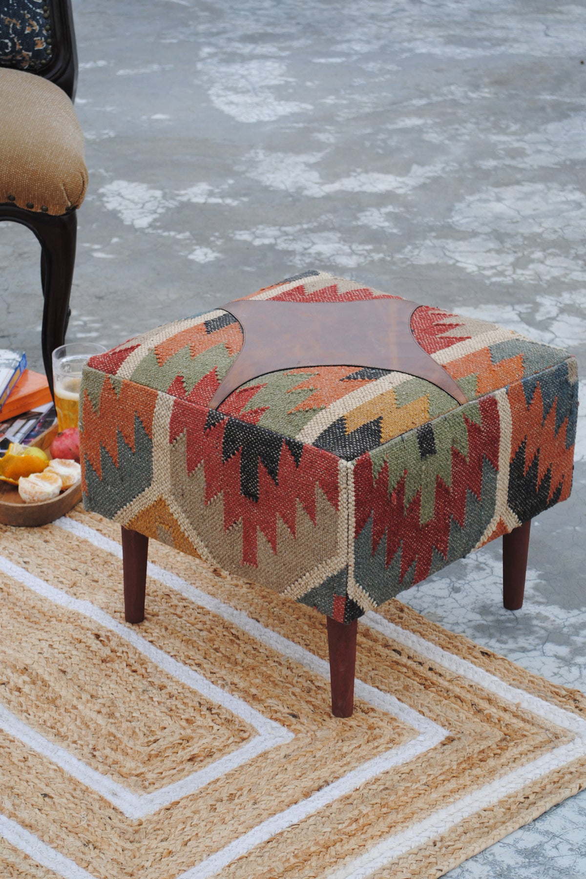 Ajanta medallion ottoman on a jute rug, showing the leather medallion inset in the kilim seat