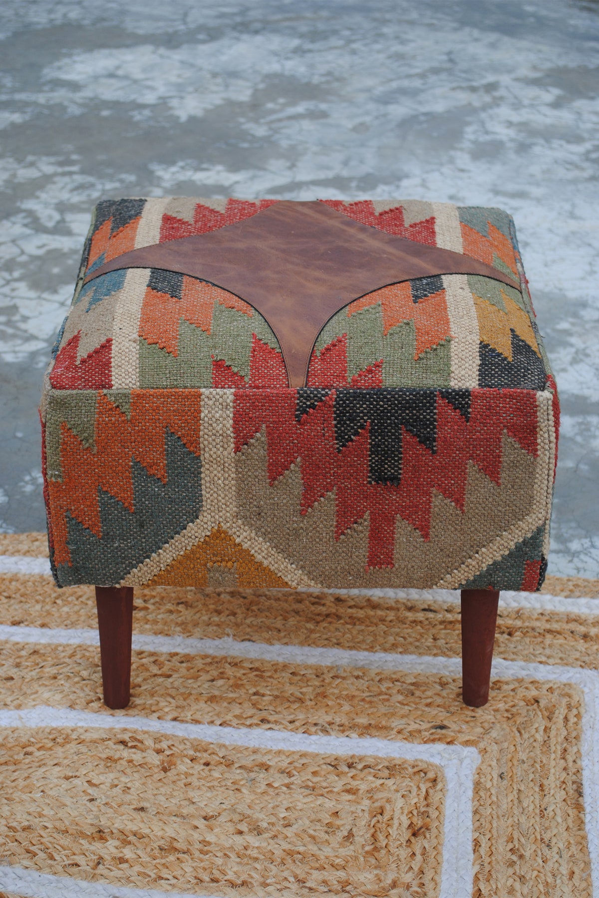 Front elevation of the Ajanta medallion ottoman showing kilim sides and turned wooden legs