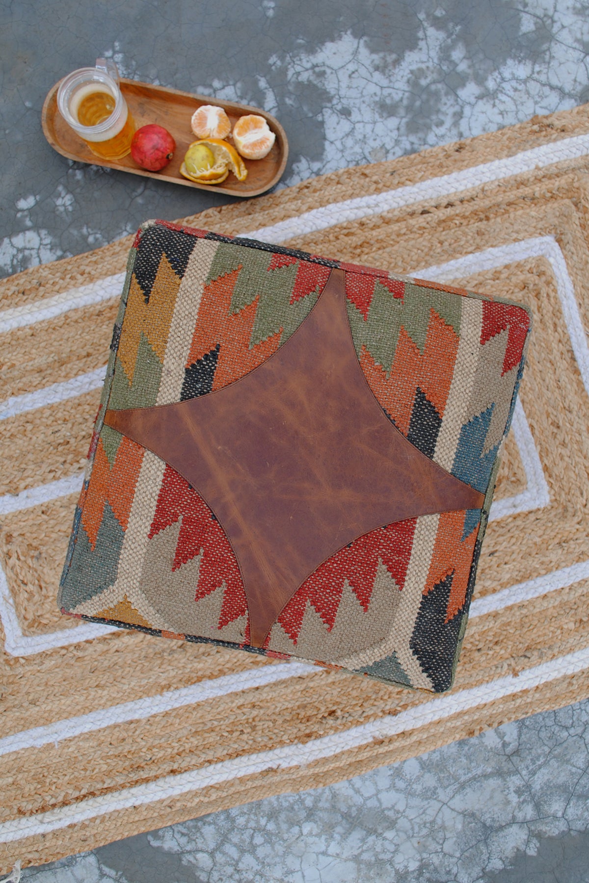 Overhead view of the Ajanta ottoman showing the four-point leather medallion set into handwoven kilim