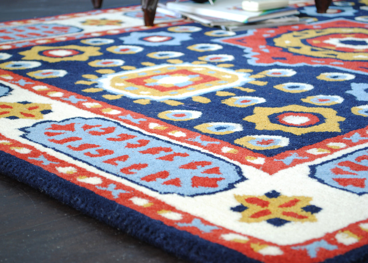 Low-angle view across the Orchha rug's navy field and sky-blue cartouche border