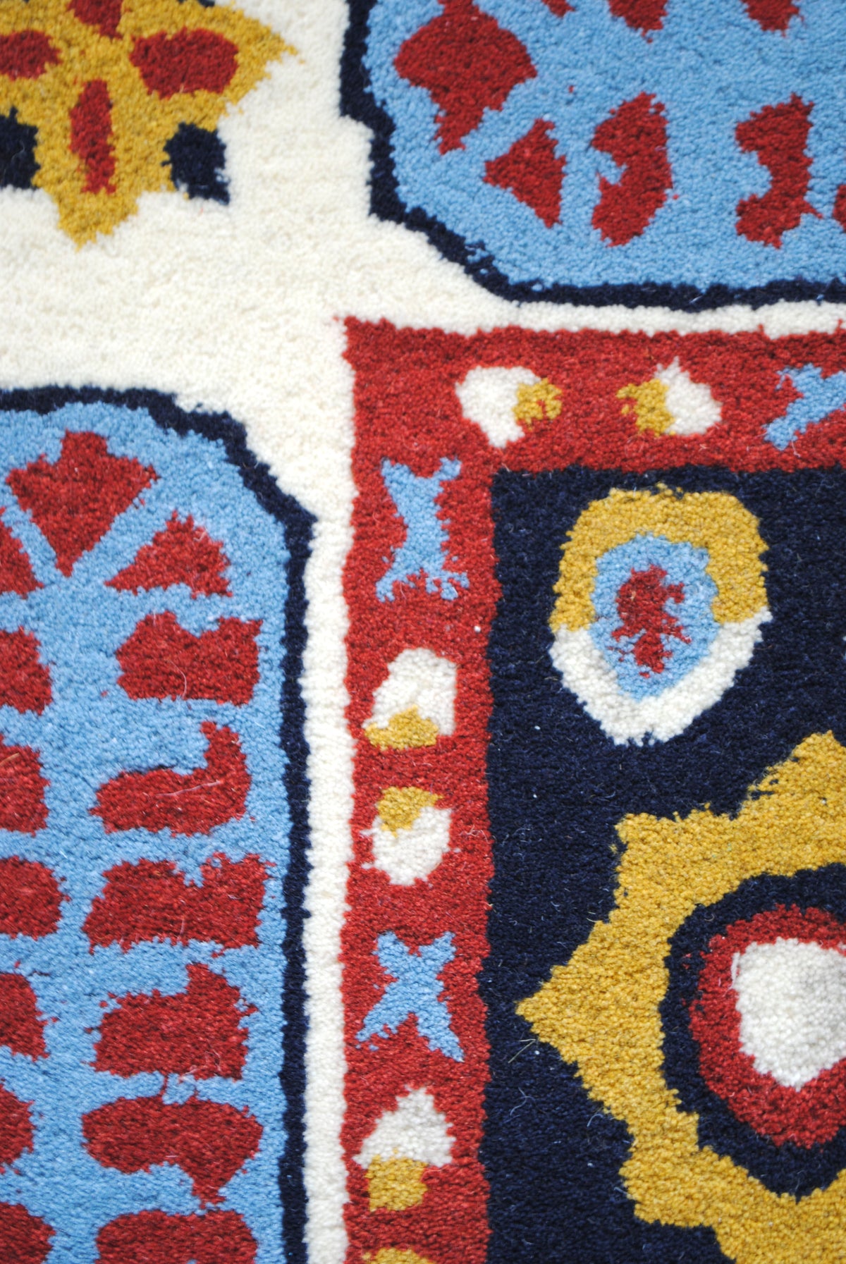Close-up of the Orchha rug's New Zealand wool pile: sky-blue cartouche, red guard stripe and gold motif