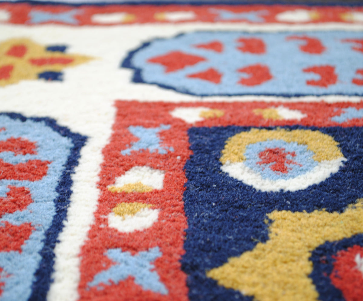 Detail of the Orchha rug's hand-sheared wool pile where the ivory border meets the navy field