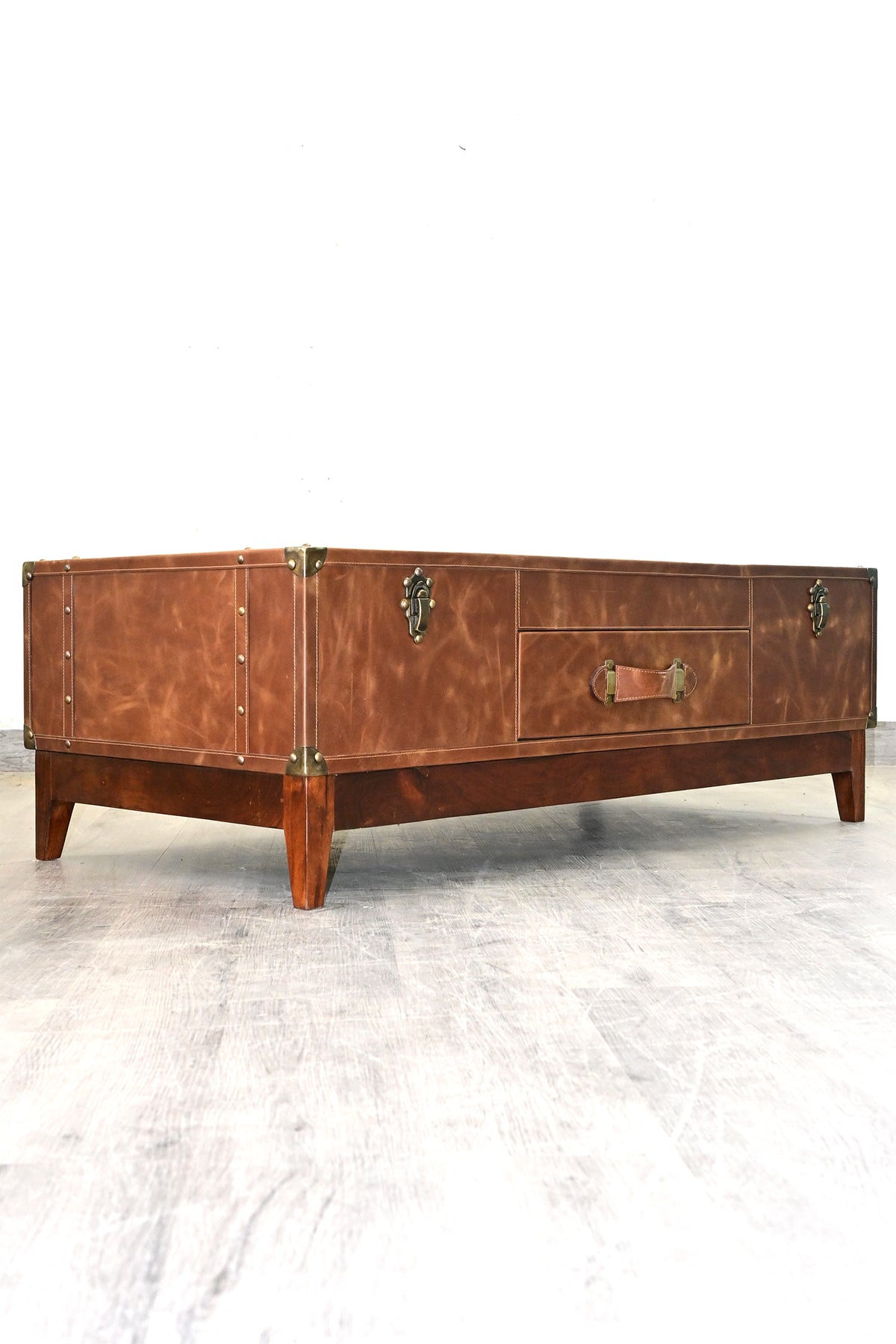 Kuchaman leather trunk coffee table, low angle from the opposite corner on a solid wood plinth