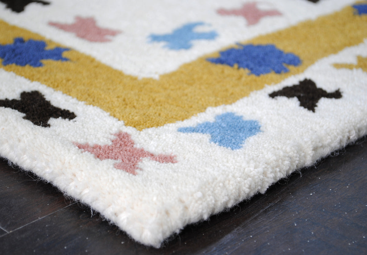 Corner of the Tawang rug showing pile depth and the ivory wool-bound edge, no fringe