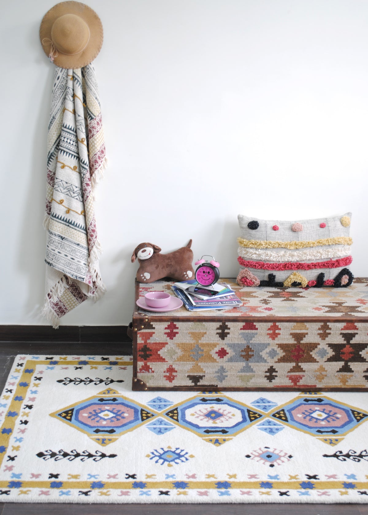 Tawang ivory medallion rug styled in front of a kilim and leather trunk, with a block-printed throw on the wall