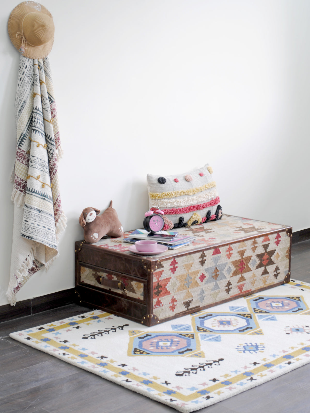 Tawang rug from a three-quarter angle beside a kilim trunk on a dark wood floor