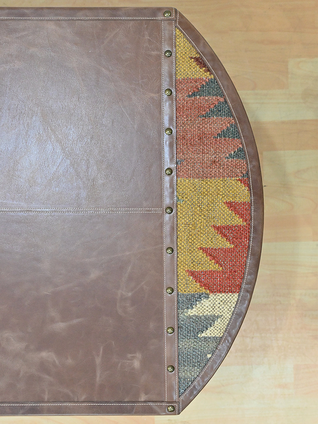 Close view of the vintage kilim inset in the Bisalpur table top, studded leather binding alongside