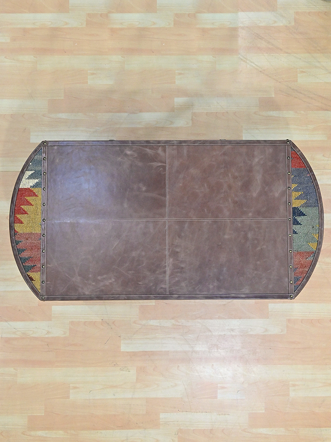 Top view of the Bisalpur coffee table, leather top panels flanked by two vintage kilim half-moons