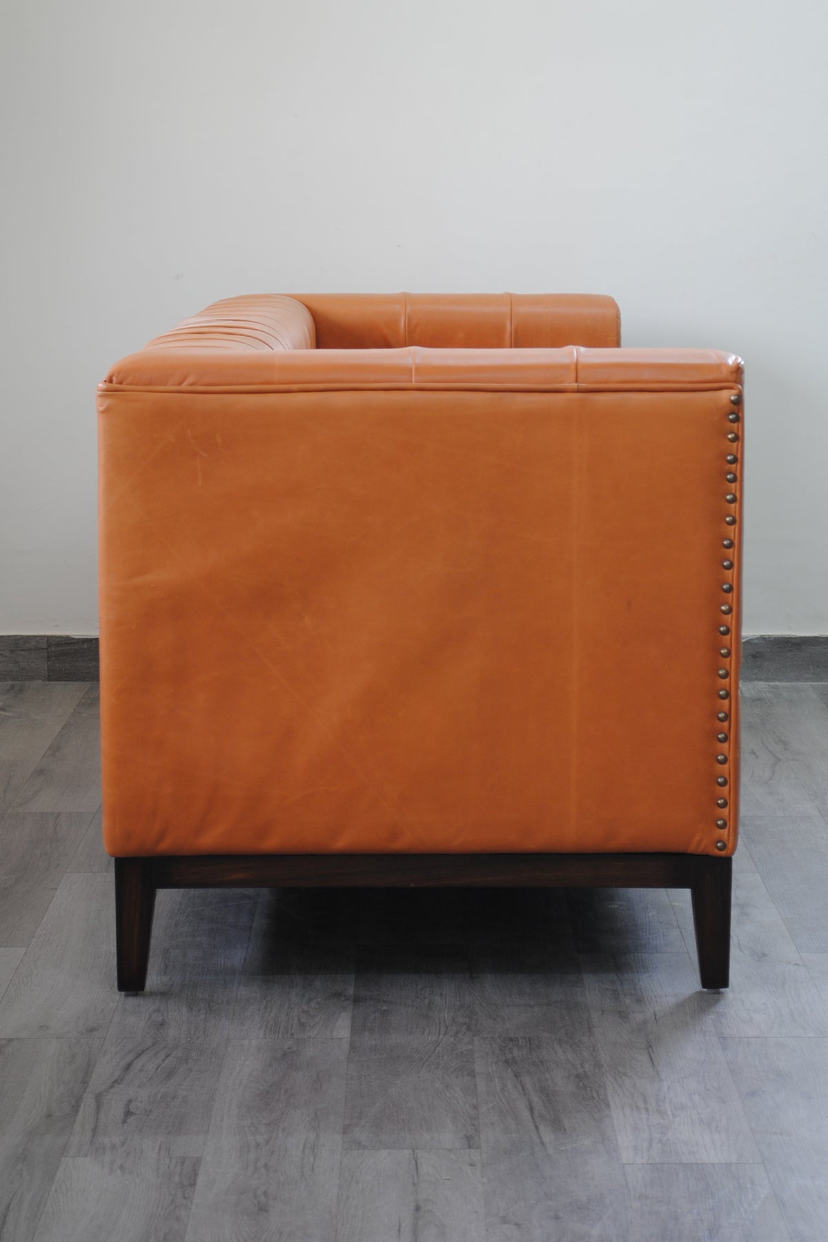 Rear three-quarter view of the Santiago leather sofa with the brass nailhead row down the outside corner