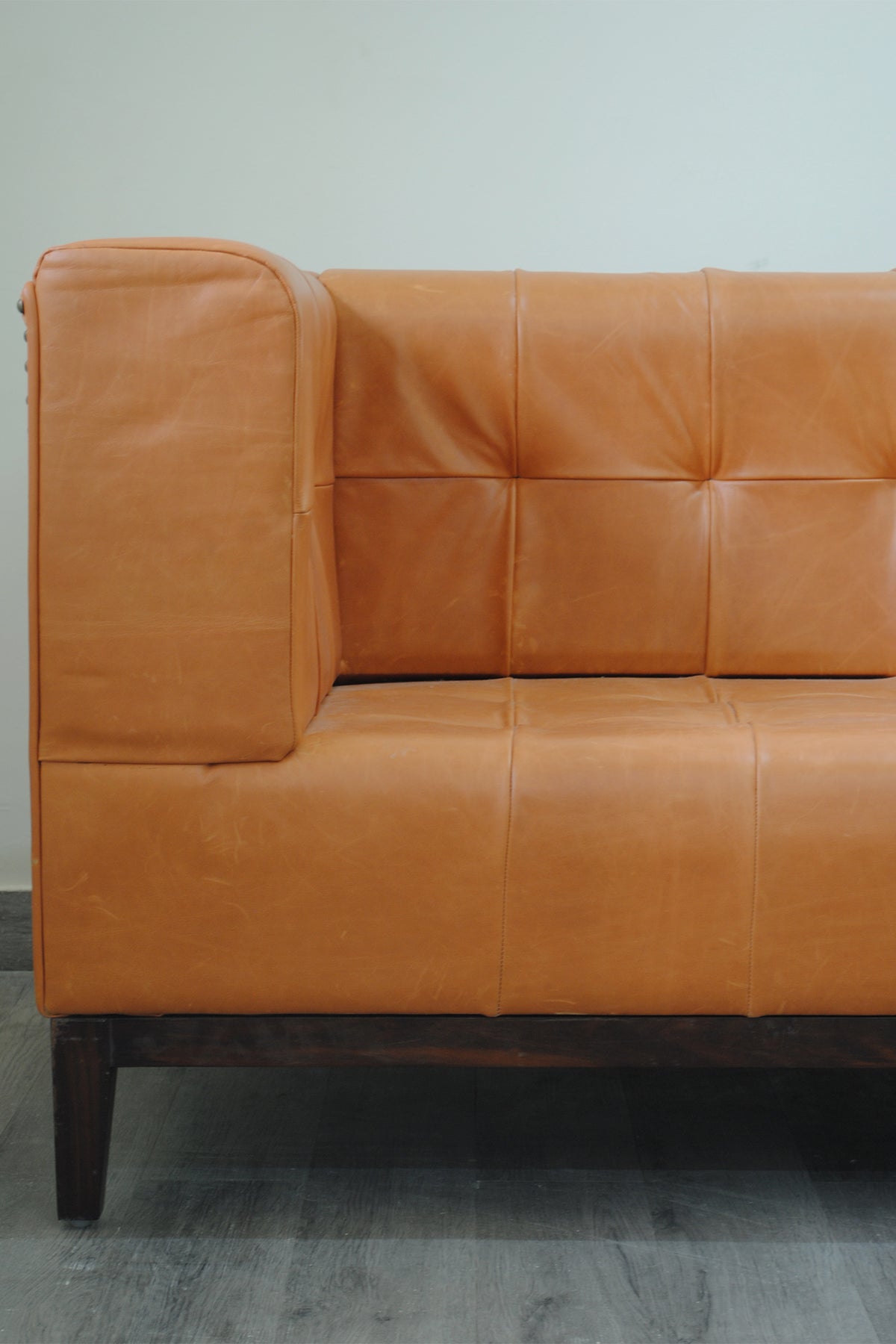 Detail of the Santiago sofa arm and back, showing squared biscuit tufting and the loose arm cushion