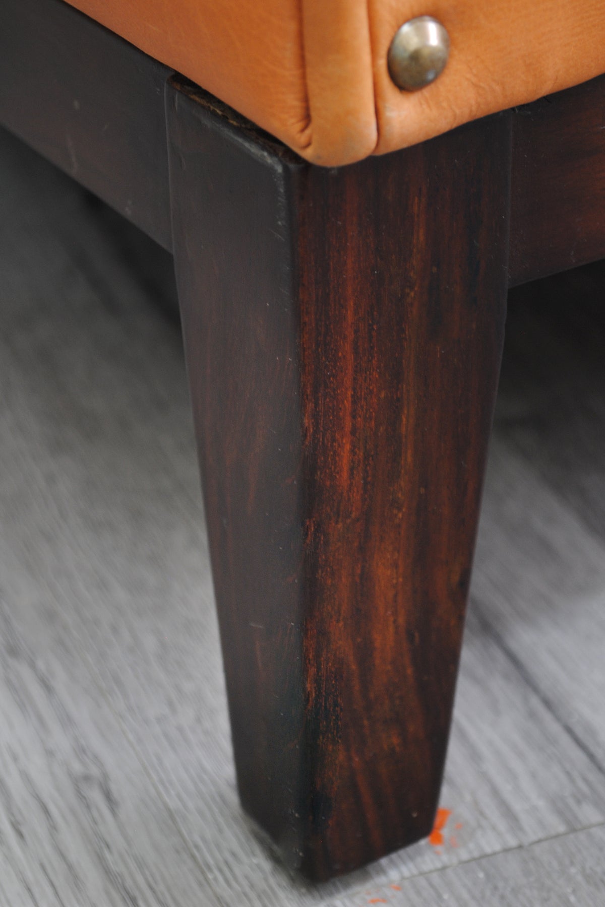 Detail of the Santiago sofa's square tapered leg and dark timber plinth base