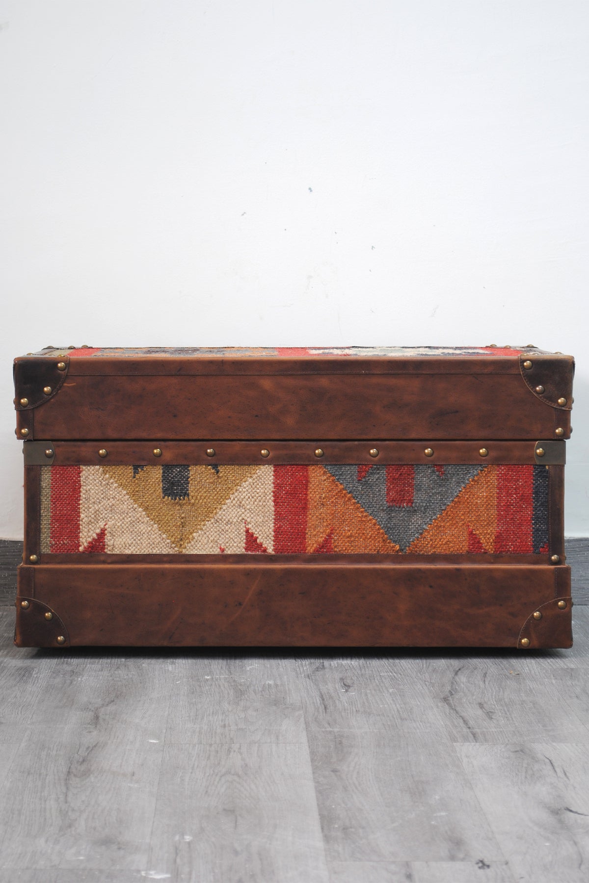 Bundi kilim steamer trunk viewed from the rear, kilim panel framed in leather with brass studs
