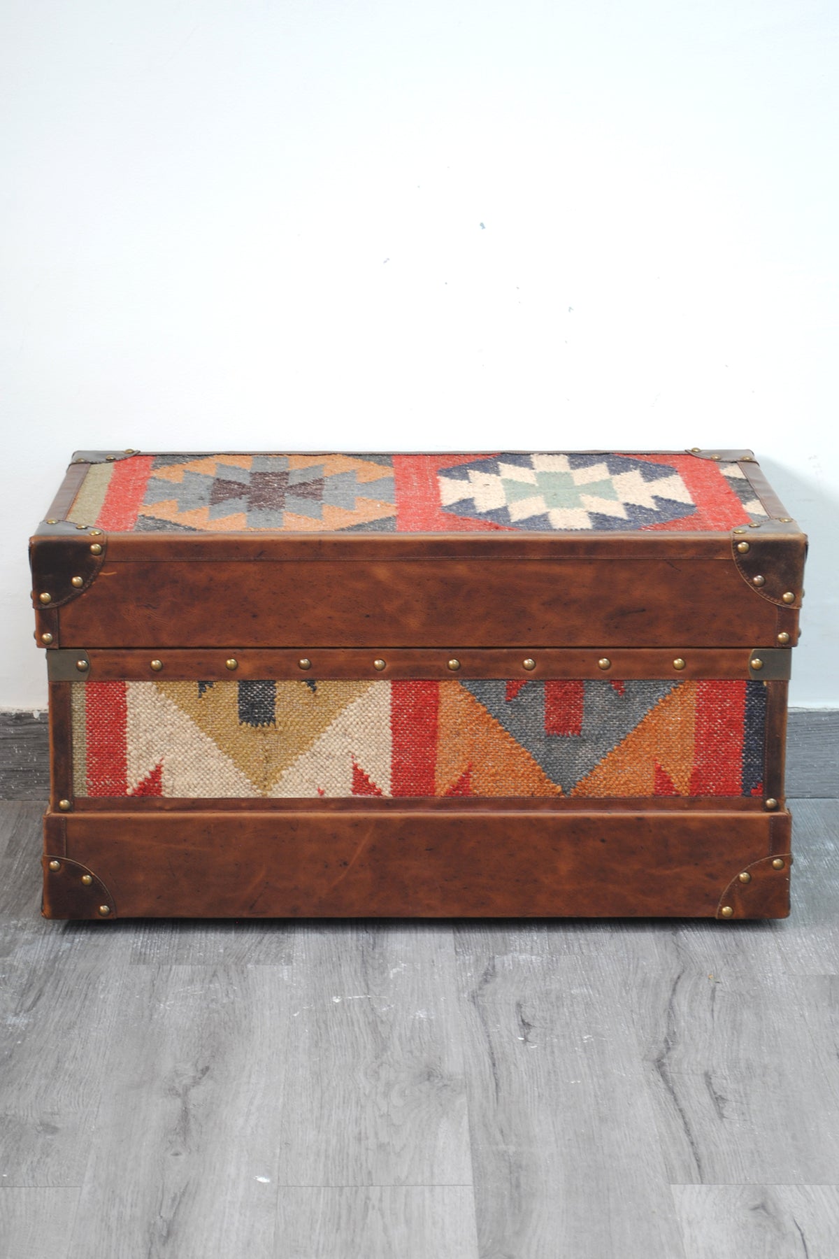 Bundi kilim steamer trunk photographed straight on, kilim lid and front panel framed in leather