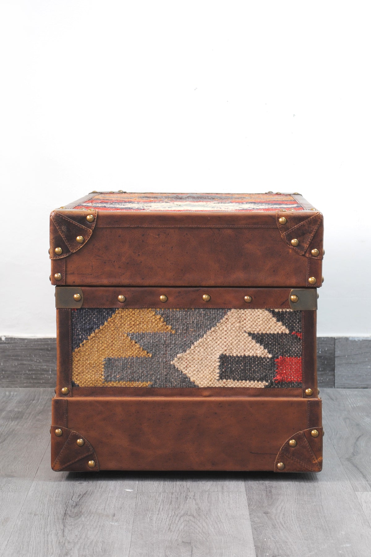 End elevation of the Bundi kilim steamer trunk showing the side kilim panel and riveted leather corner caps