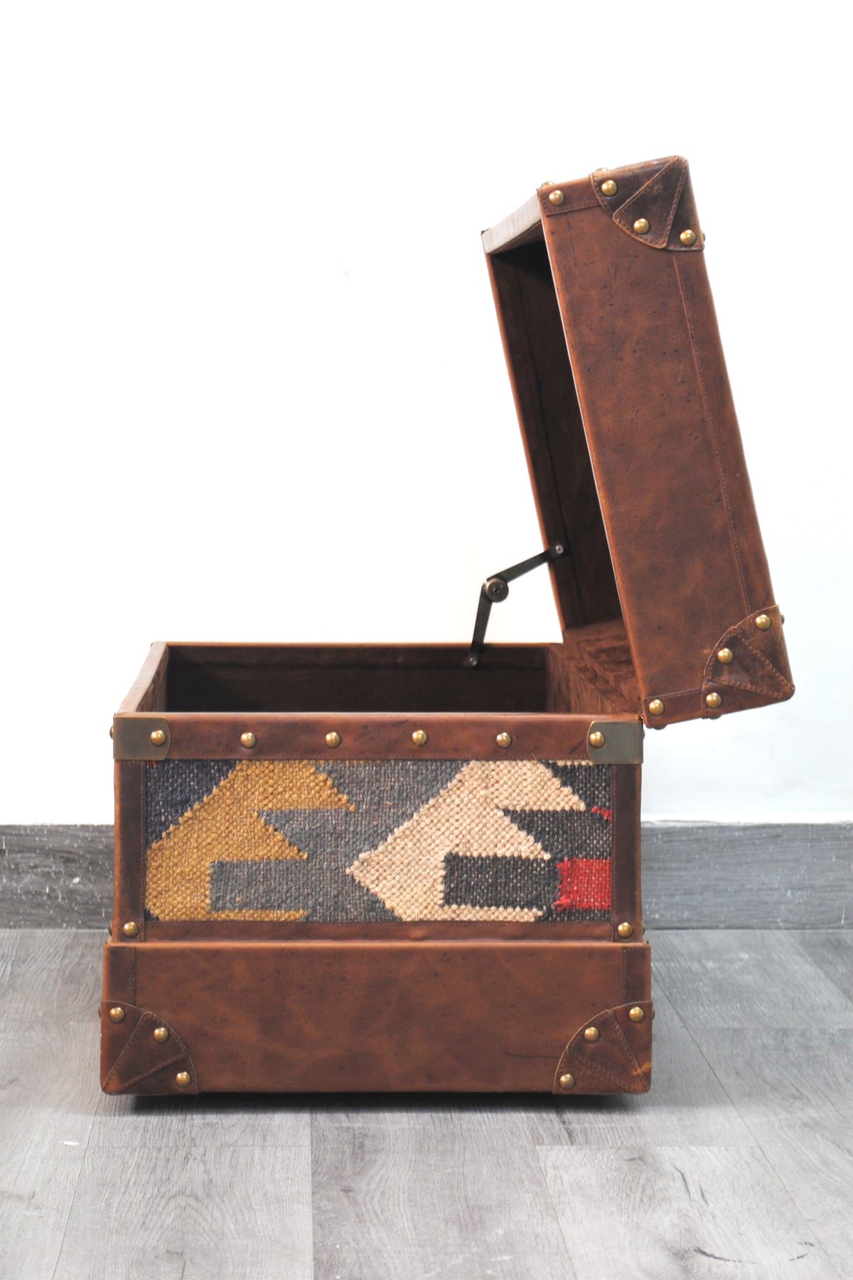 Side view of the Bundi kilim steamer trunk with the lid propped open on its stay arm