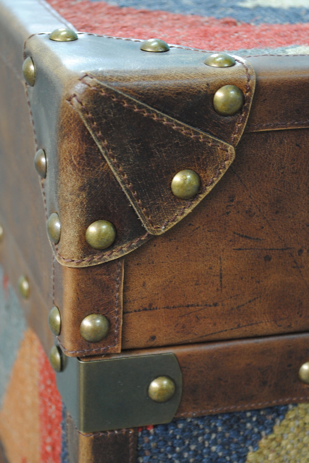 Detail of the leather corner cap, brass strap plate and studded band at the lid line