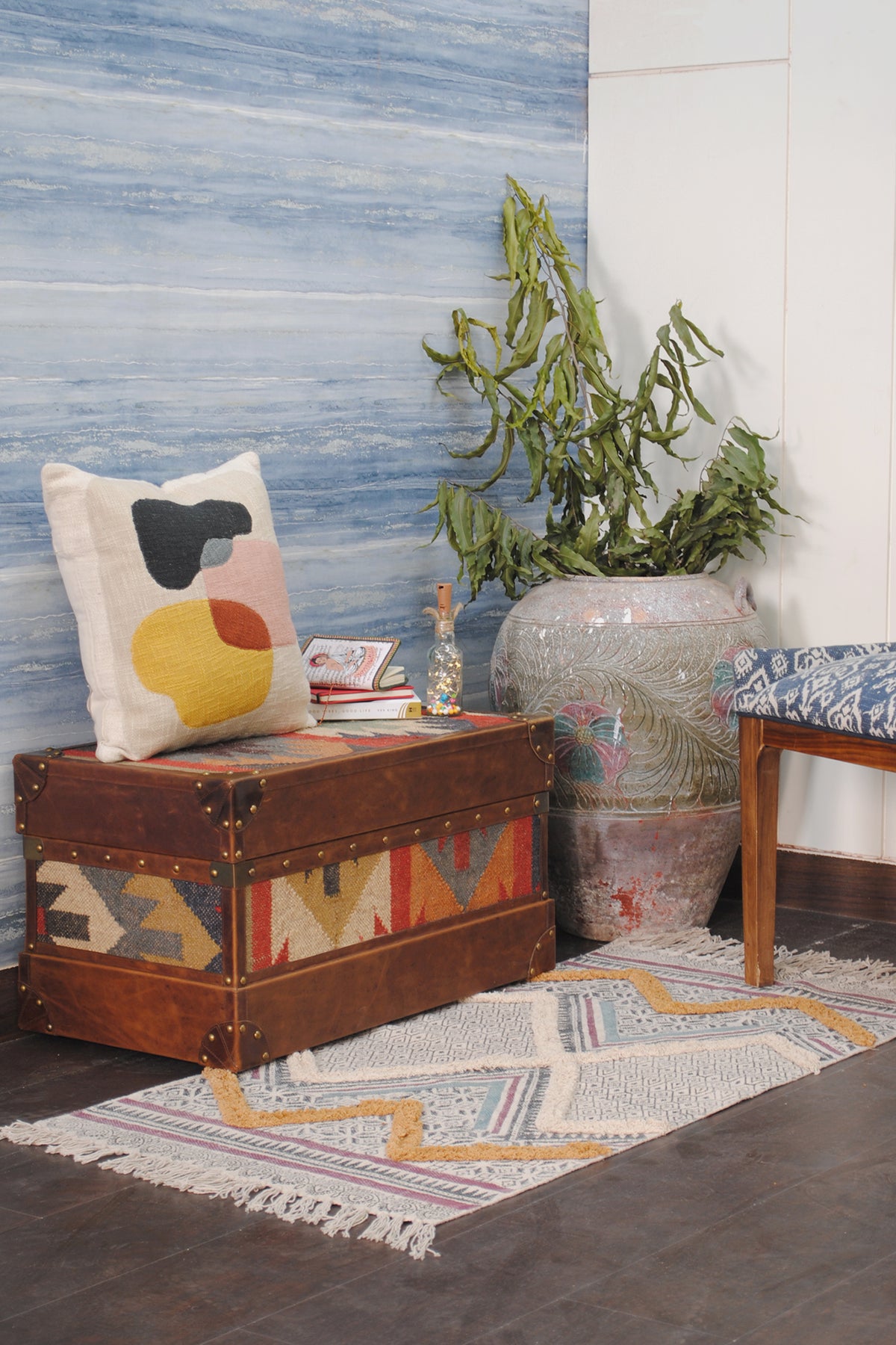 Bundi kilim steamer trunk styled in a hallway with a cushion, books and a potted plant