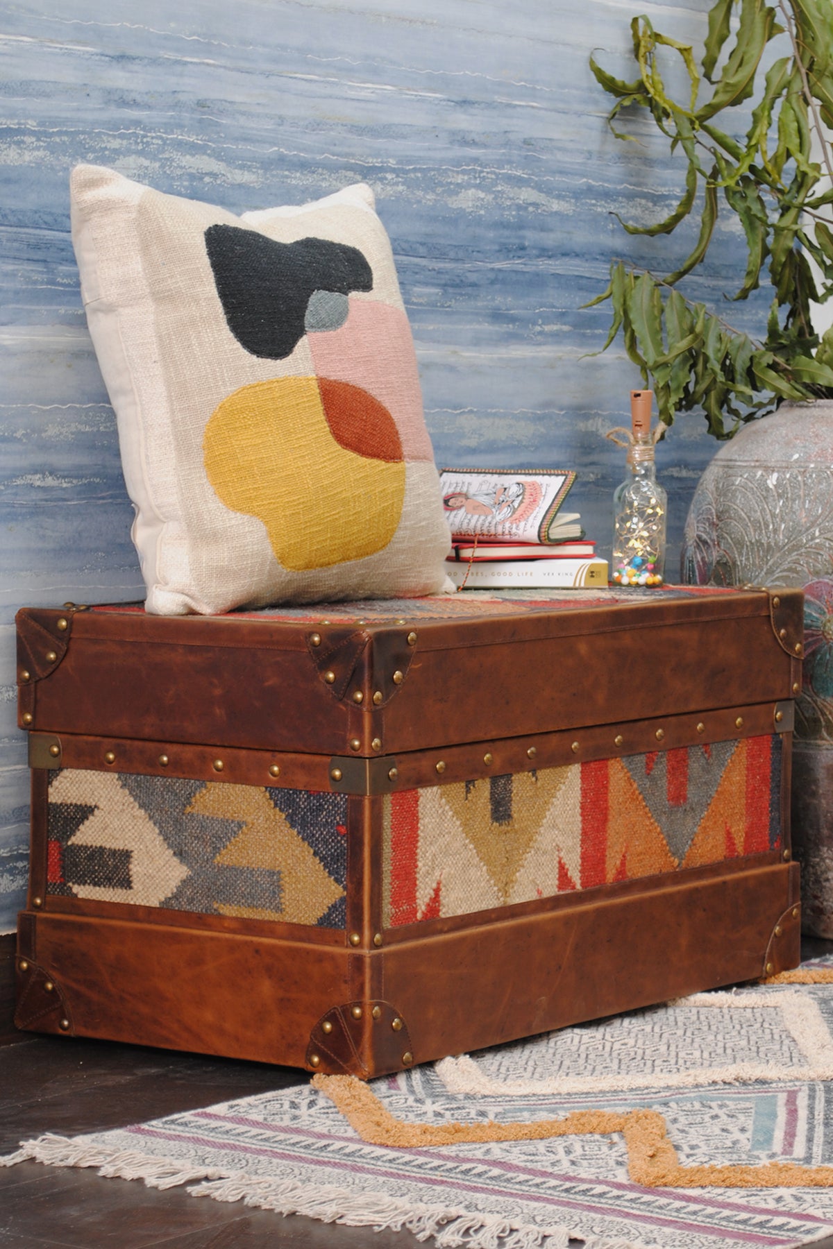 Bundi kilim steamer trunk used as a bench seat, styled with a cushion and stacked books