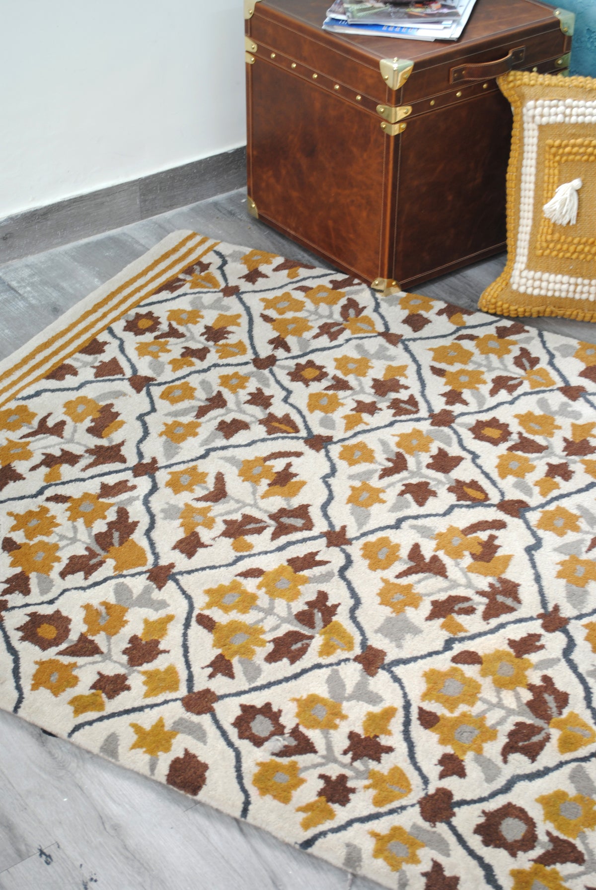 Sikandra floral trellis rug in a corner with the Cordoba Leather Cube Trunk and an ochre woven cushion