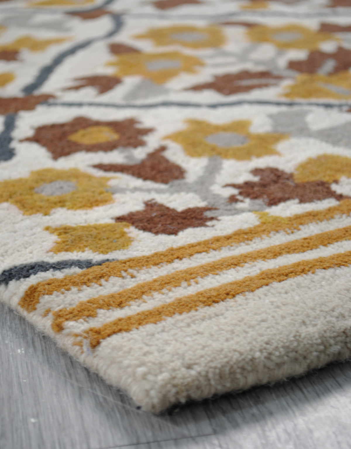 End of the Sikandra rug showing the triple ochre stripe band and ivory bound edge, no fringe