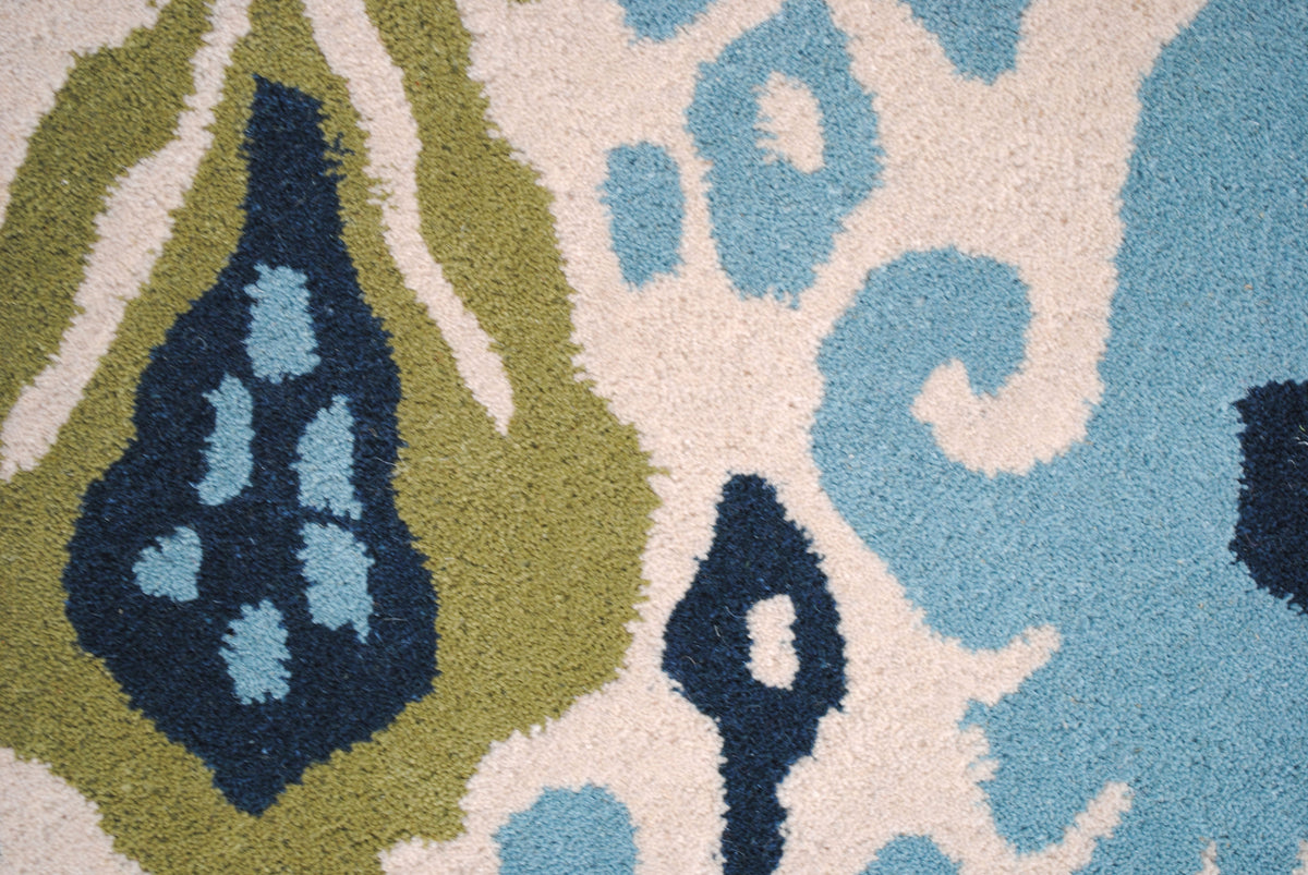 Close-up of the Pochampally rug's feathered ikat edges in moss green, indigo and sky-blue cut pile