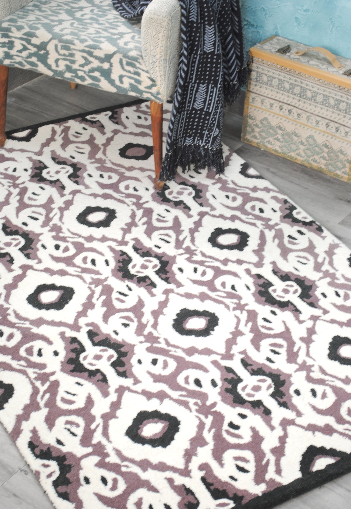 Patan ikat rug under a mid-century armchair on a grey wood floor