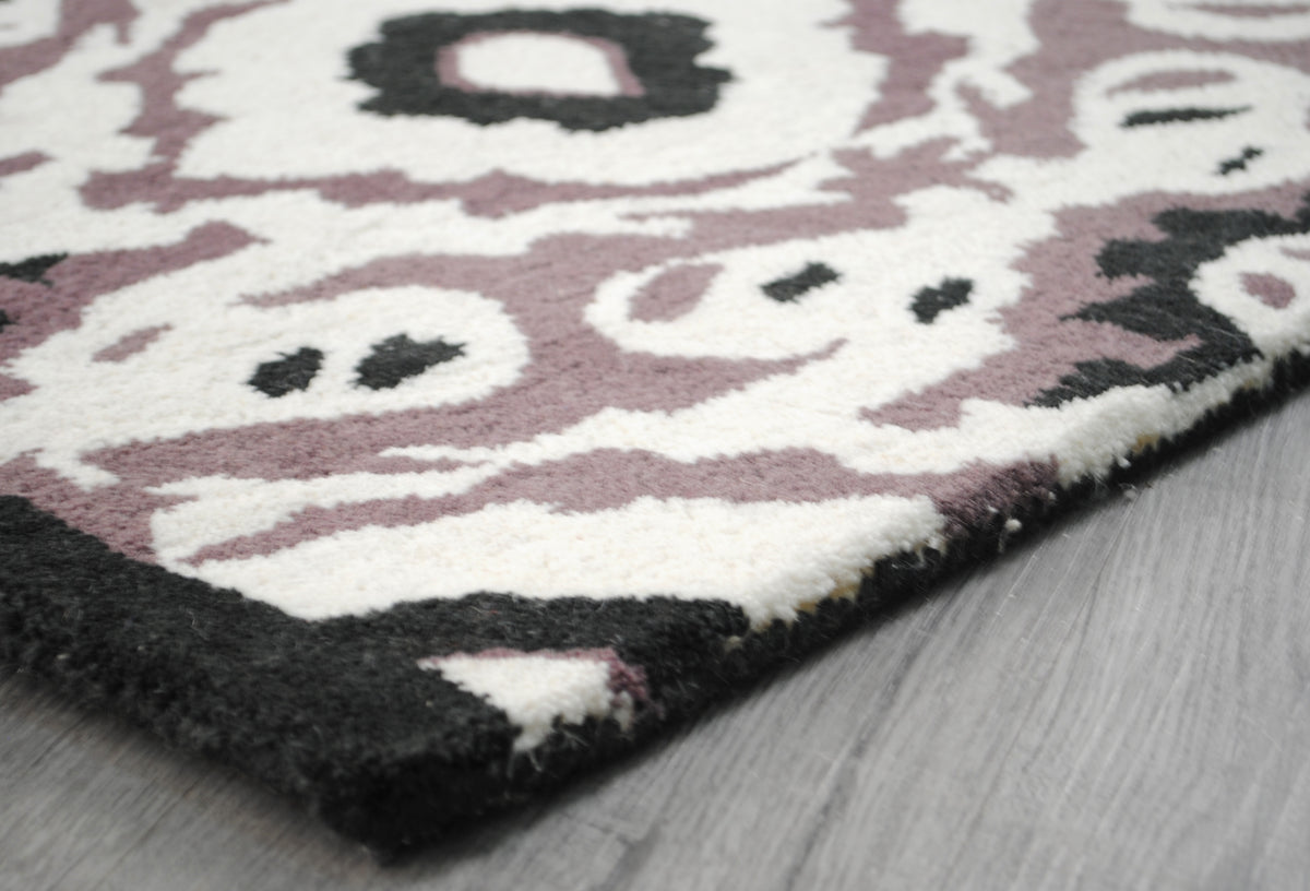 Corner of the Patan rug showing the black wool-bound edge, no fringe