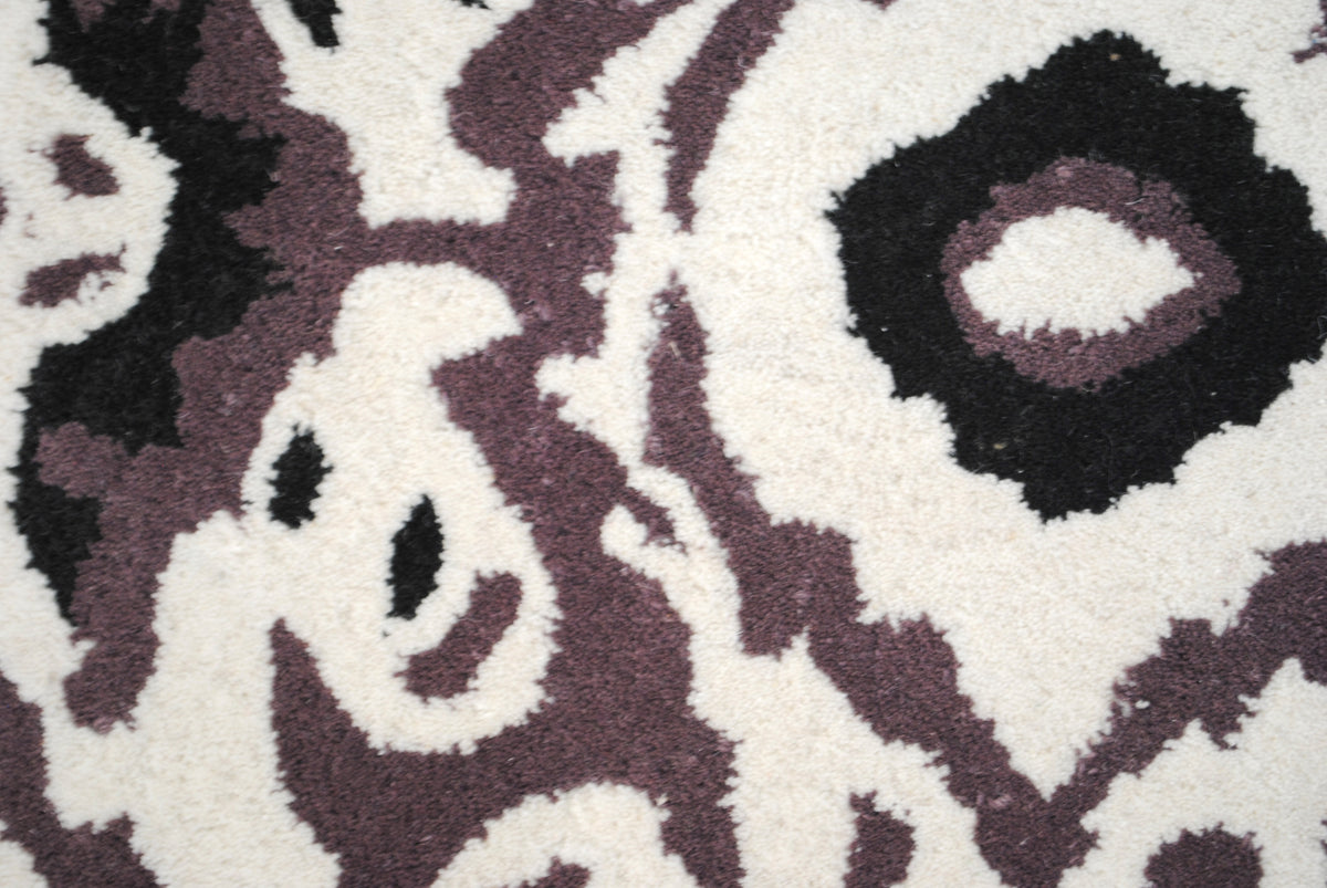 Close-up of the Patan rug's feathered ikat edges in aubergine, black and ivory cut pile