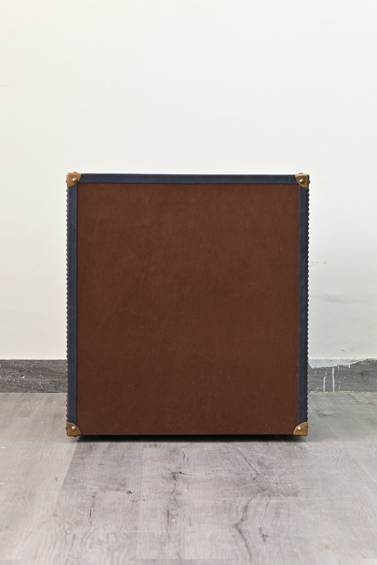 Backing panel of the Samode leather bedside chest, trimmed in navy leather with brass corner caps