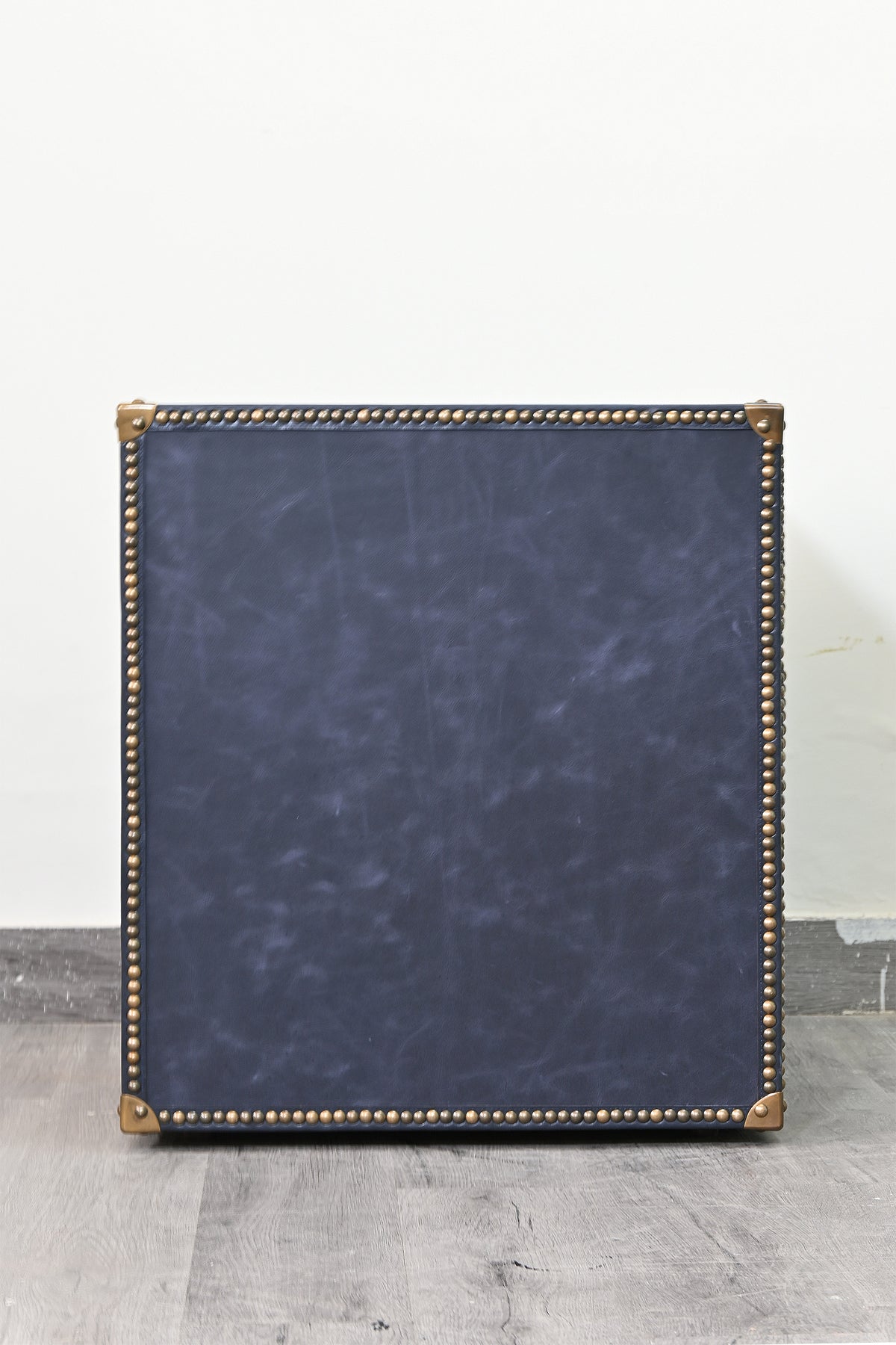 Navy leather flank of the Samode bedside chest with brass stud border and cast corner caps