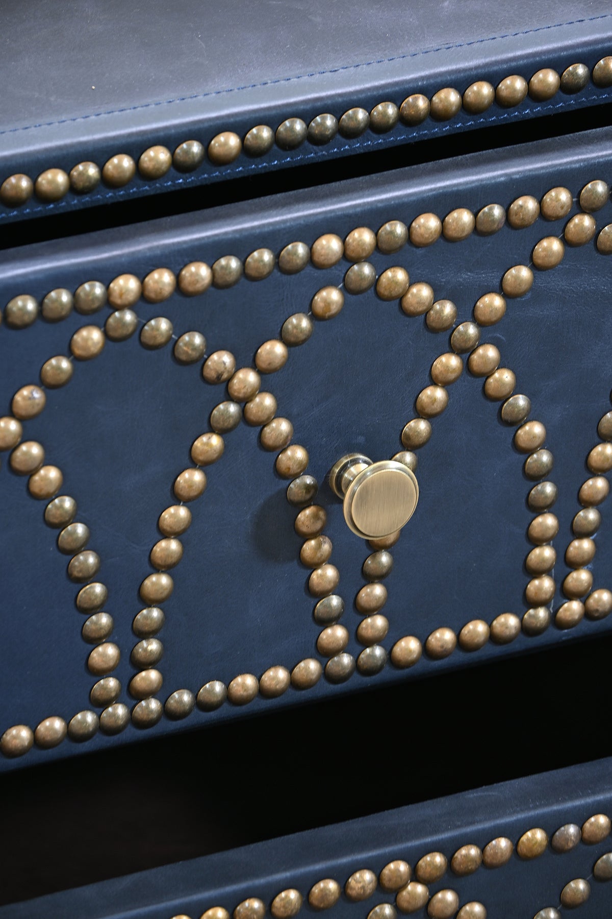 Close detail of the hand-set brass studs and turned brass knob on the Samode bedside chest