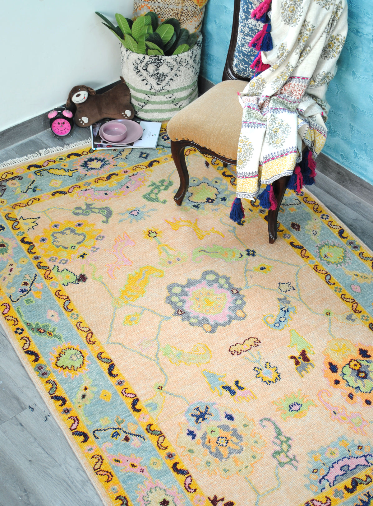 Mysore Hand-Knotted Rug in a bedroom corner beside an upholstered chair, apricot field and aqua border seen from above — Art Avenue