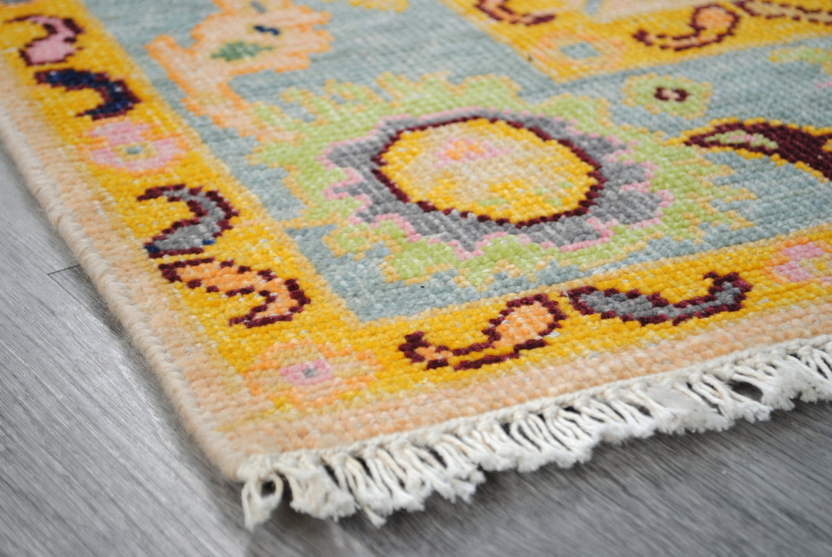 Corner of the Mysore Hand-Knotted Rug showing saffron guard stripe, aqua border and cotton fringe — Art Avenue