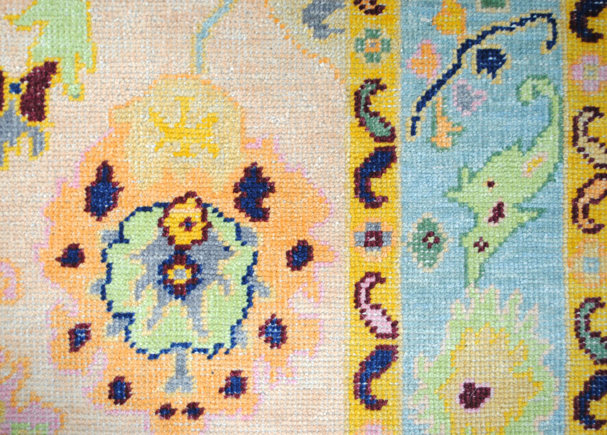 Close-up of a palmette on the Mysore Hand-Knotted Rug, apricot, lime and navy wool knots beside the aqua border — Art Avenue