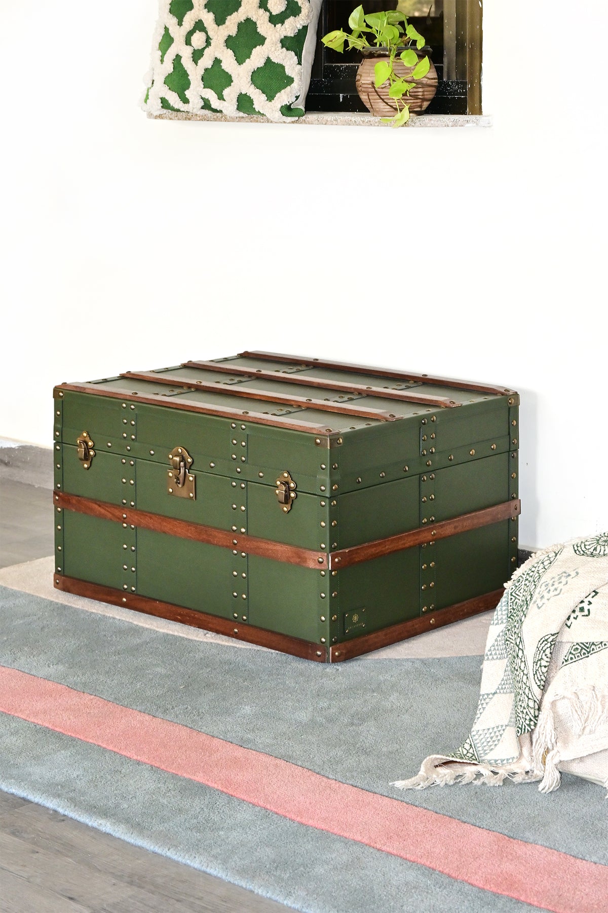 Green leather steamer trunk styled on a striped rug beneath a wall niche — Art Avenue, made to order